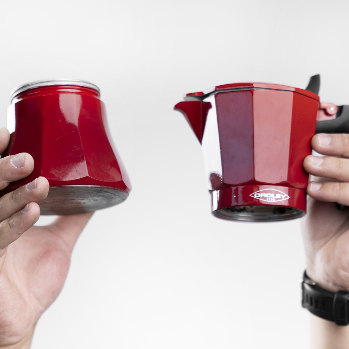 Cafetera italiana roja Oroley desarmada y sostenida por dos manos