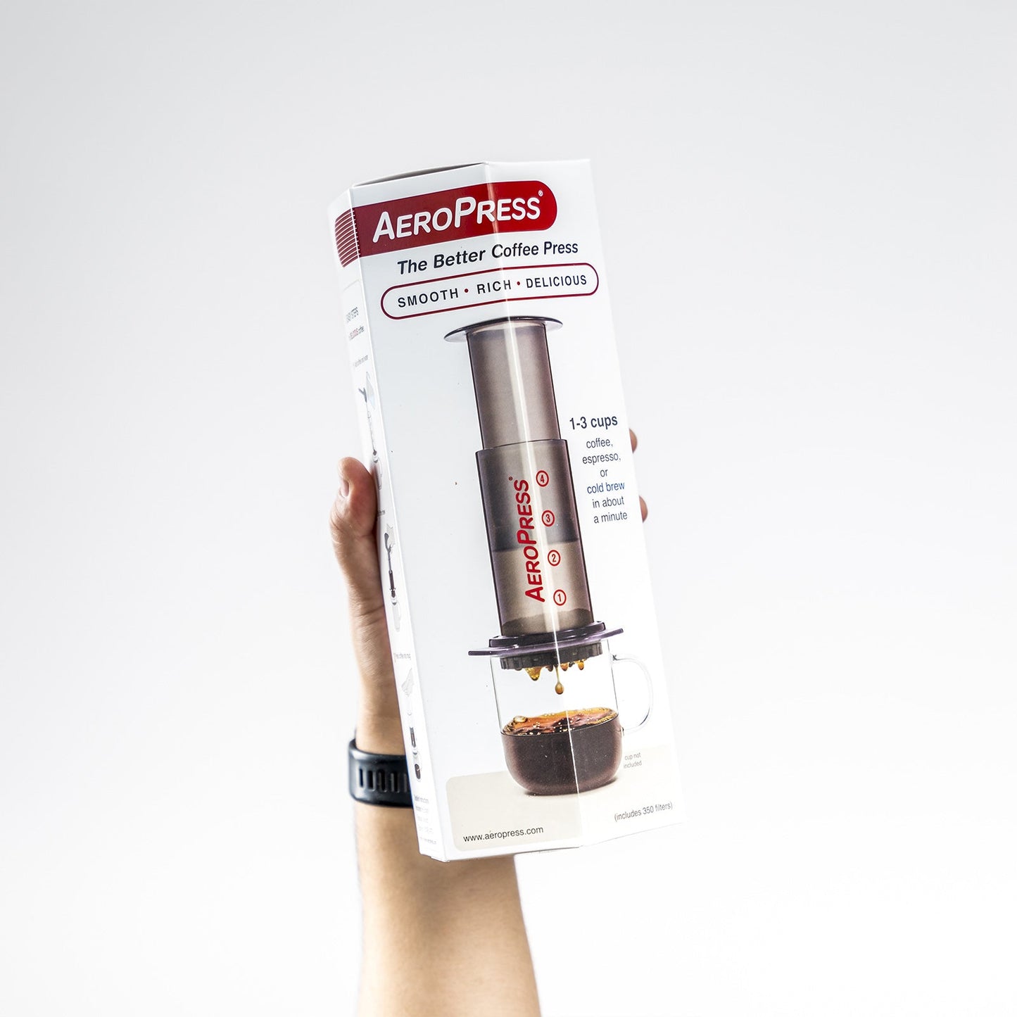 AeroPress en su caja sostenida por una mano